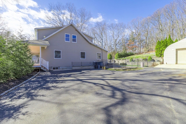 view of side of property featuring aphalt driveway and fence