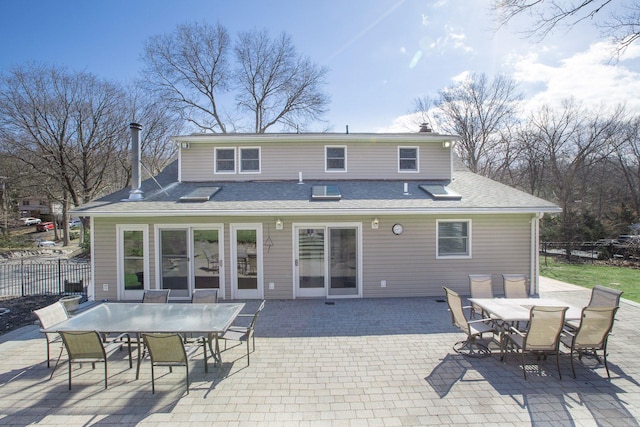 rear view of house featuring outdoor dining area, a patio, and fence