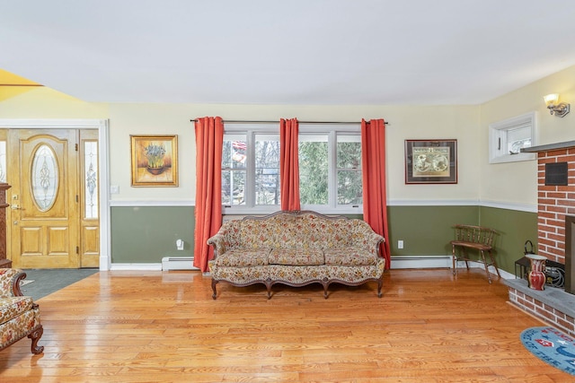 sitting room featuring a baseboard heating unit, wainscoting, wood finished floors, and a fireplace