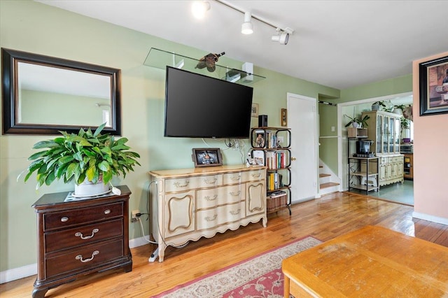 living room with stairs, baseboards, and light wood finished floors