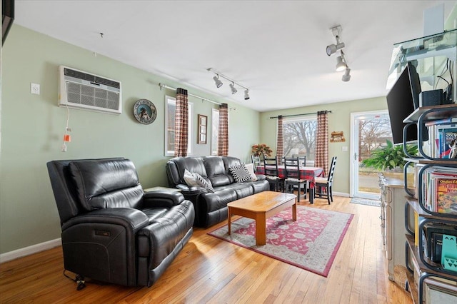 living room with baseboards, light wood-style flooring, rail lighting, and a wall mounted AC