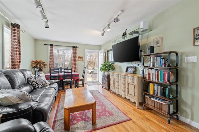 living area featuring baseboards, light wood-style floors, and track lighting