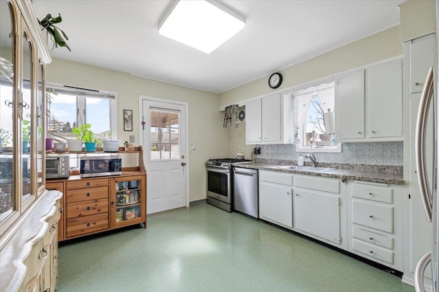 kitchen with a sink, stainless steel appliances, a wealth of natural light, and white cabinets