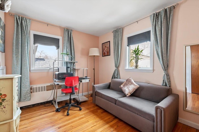 interior space with wood finished floors, radiator heating unit, a healthy amount of sunlight, and baseboards