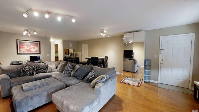 living area featuring rail lighting, baseboards, and light wood-style floors