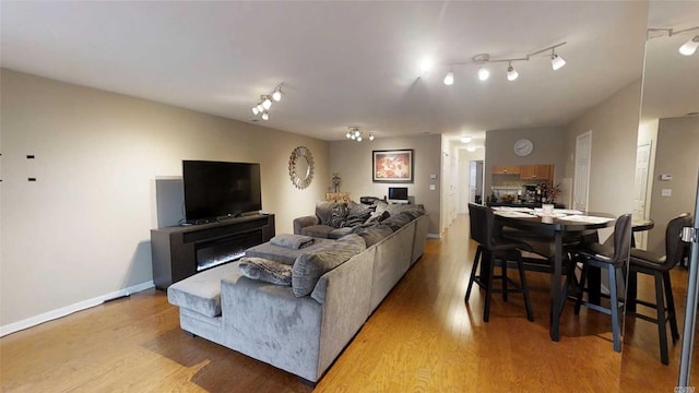 living room featuring baseboards, light wood-style flooring, and track lighting