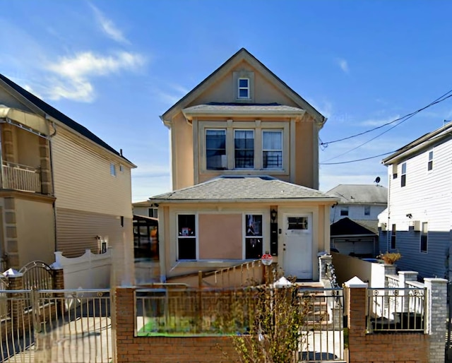 view of front of home featuring a fenced front yard, stucco siding, a shingled roof, and a gate