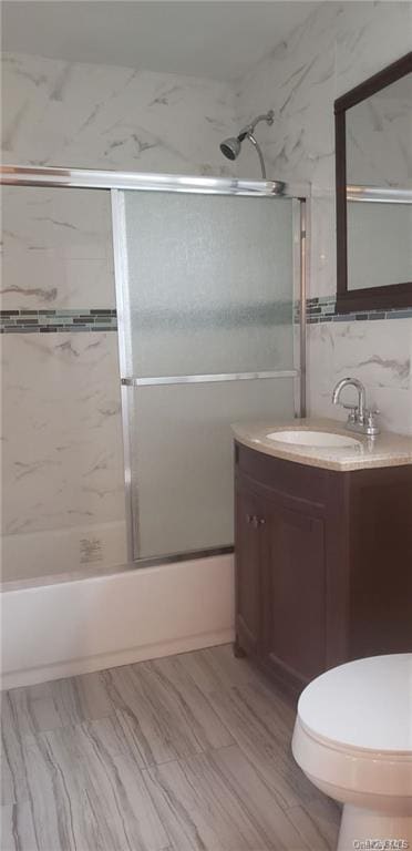 full bathroom with toilet, backsplash, tile walls, bath / shower combo with glass door, and vanity