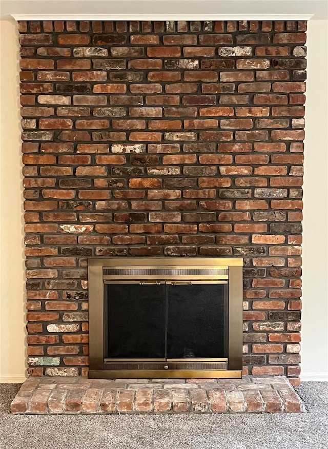 interior details featuring baseboards, carpet, and a brick fireplace