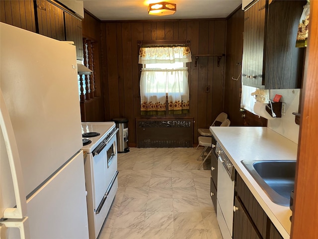 kitchen with under cabinet range hood, wood walls, light countertops, white appliances, and a sink