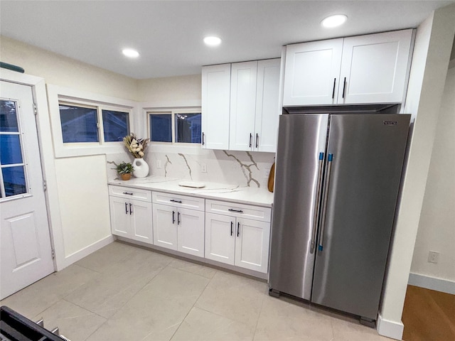 kitchen featuring backsplash, light stone countertops, recessed lighting, high quality fridge, and white cabinetry