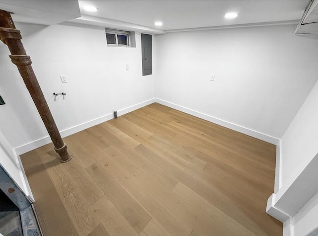 finished basement featuring light wood-style flooring, electric panel, recessed lighting, and baseboards