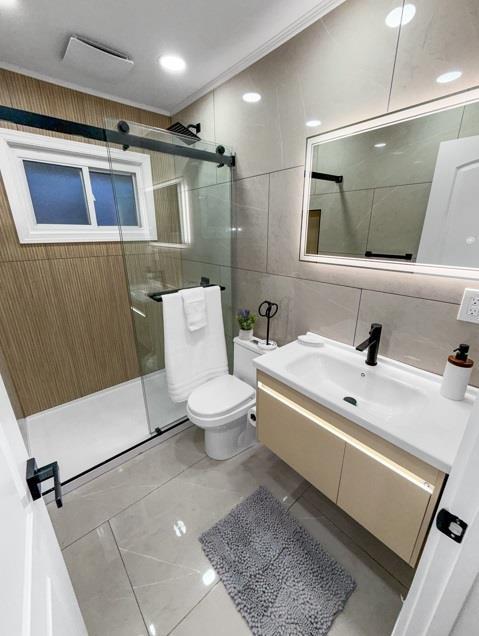 full bathroom featuring vanity, toilet, tile walls, and a shower stall