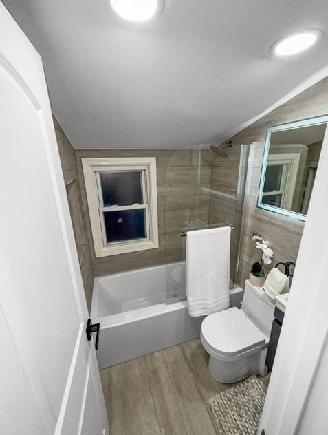 bathroom with toilet, wood finished floors, and shower / bathtub combination