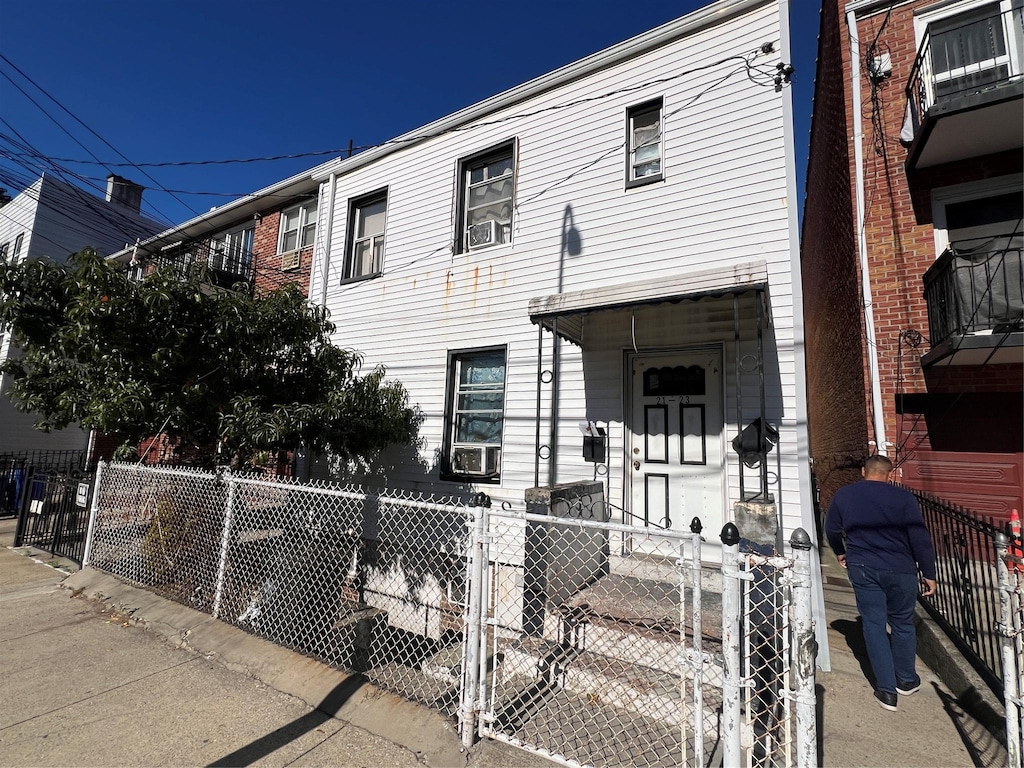 townhome / multi-family property with cooling unit and a fenced front yard