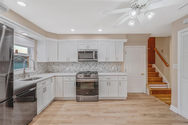 kitchen with light wood finished floors, a sink, stainless steel appliances, light countertops, and white cabinets