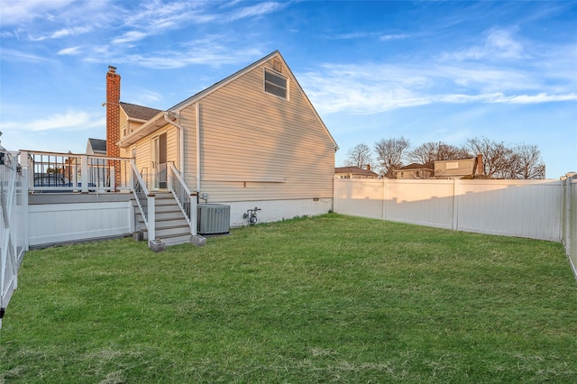 view of side of home with a fenced backyard, a yard, cooling unit, a wooden deck, and a chimney