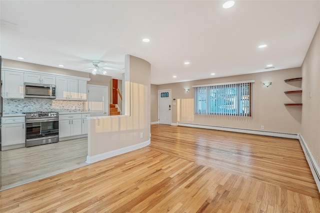 unfurnished living room featuring baseboard heating, baseboards, and light wood finished floors