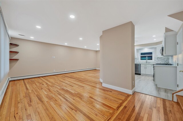 unfurnished living room featuring a sink, recessed lighting, light wood-style floors, a baseboard radiator, and baseboards