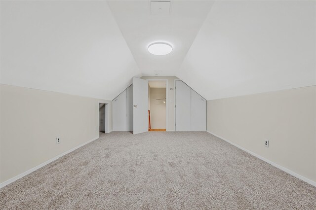 additional living space featuring light colored carpet, baseboards, and lofted ceiling