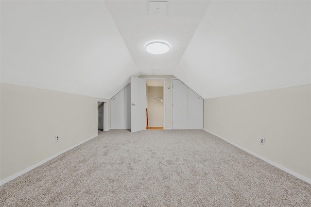 additional living space featuring lofted ceiling, light colored carpet, and baseboards