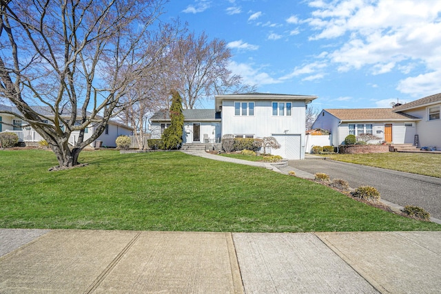 tri-level home with a front lawn, board and batten siding, driveway, and fence