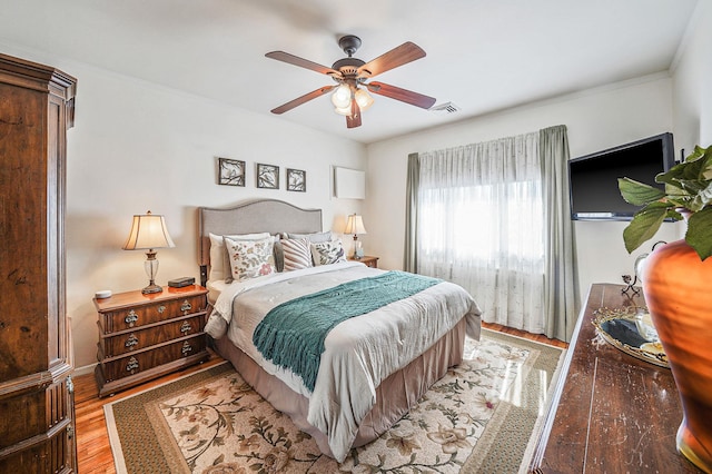 bedroom featuring visible vents, ornamental molding, ceiling fan, and wood finished floors