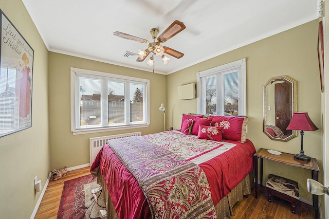 bedroom featuring crown molding, radiator heating unit, baseboards, and wood finished floors