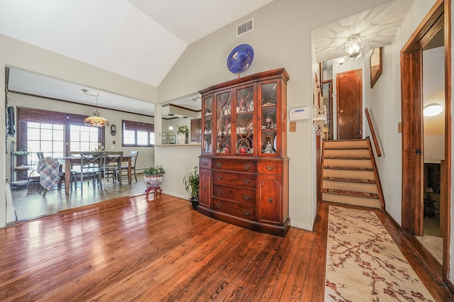 interior space featuring stairway, wood finished floors, visible vents, vaulted ceiling, and a chandelier