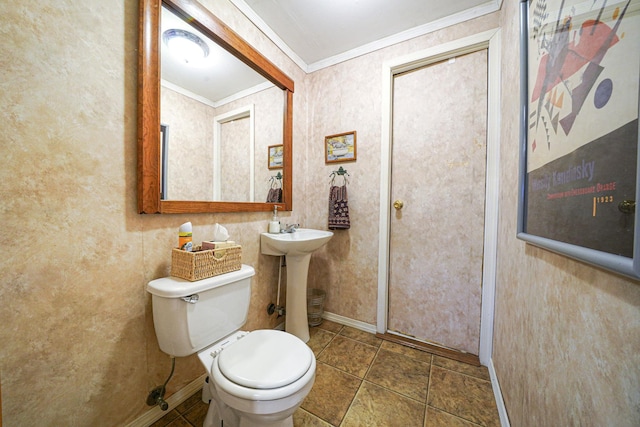 half bathroom featuring a sink, baseboards, toilet, and crown molding