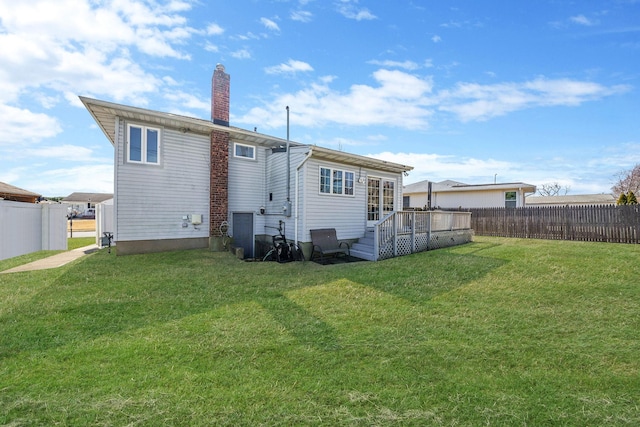 back of property featuring a yard, a wooden deck, a fenced backyard, and a chimney