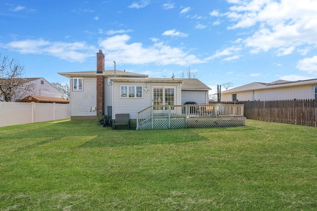 back of house with a lawn, a chimney, a fenced backyard, and a wooden deck