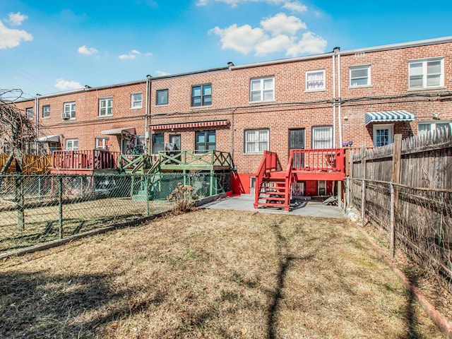 rear view of property featuring brick siding, a lawn, and a fenced backyard