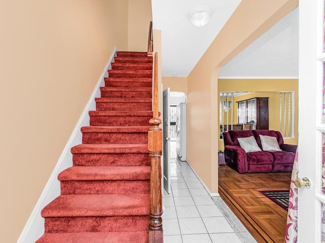 staircase with tile patterned flooring, arched walkways, and baseboards