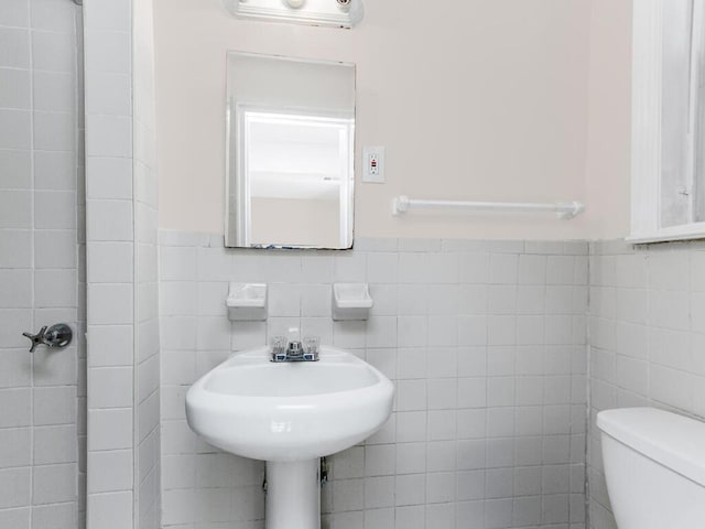 bathroom featuring tile walls, toilet, and a wainscoted wall