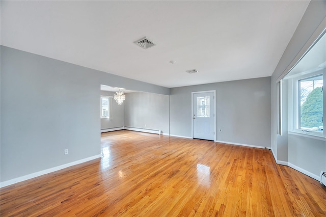 empty room featuring a chandelier, visible vents, light wood-type flooring, and a wealth of natural light