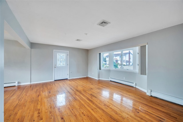 spare room featuring a baseboard heating unit, visible vents, and light wood-style flooring