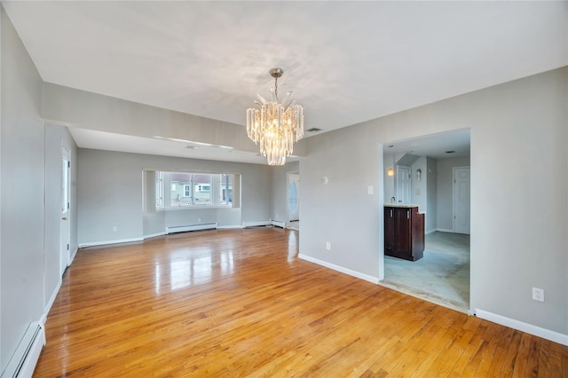 unfurnished room with light wood-type flooring, a baseboard heating unit, a notable chandelier, and a baseboard radiator