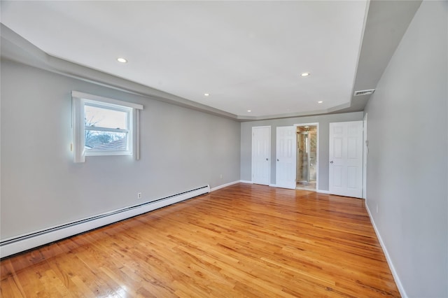 unfurnished bedroom with recessed lighting, a baseboard heating unit, and light wood finished floors