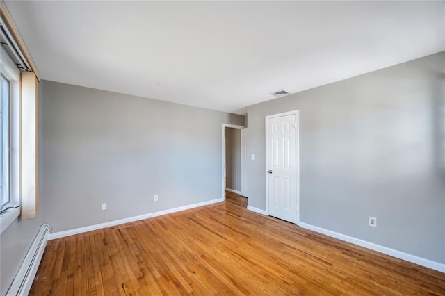 unfurnished room featuring visible vents, light wood-type flooring, baseboards, and a baseboard radiator