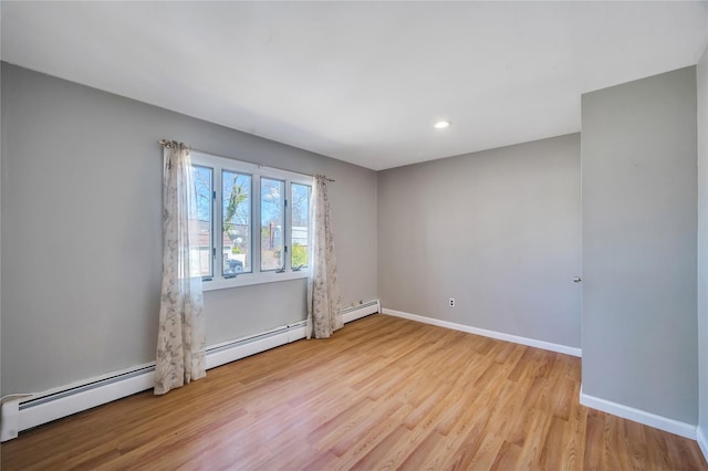 spare room with a baseboard heating unit, baseboards, and wood finished floors