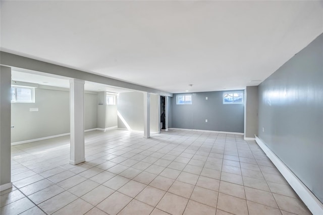 below grade area featuring light tile patterned floors, a baseboard heating unit, plenty of natural light, and baseboards