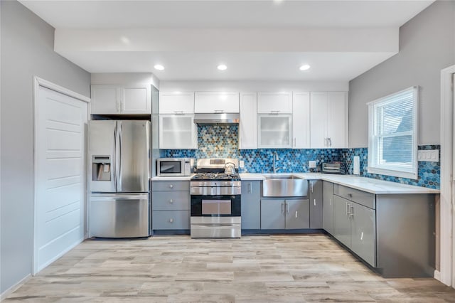 kitchen with a sink, decorative backsplash, light countertops, and stainless steel appliances