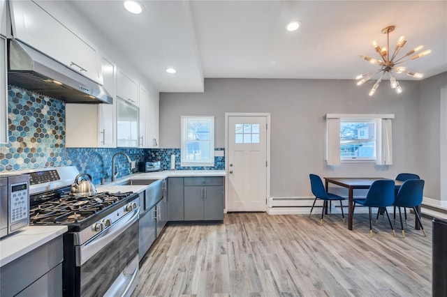 kitchen with tasteful backsplash, light countertops, gray cabinets, light wood-style floors, and gas stove