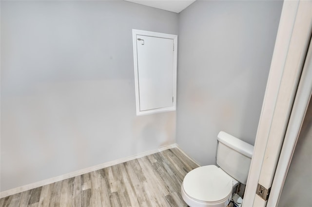 bathroom with toilet, baseboards, and wood finished floors