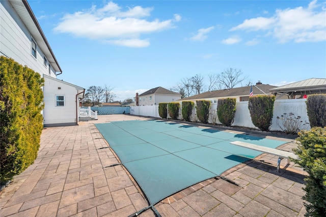 view of swimming pool featuring a diving board, a fenced in pool, a fenced backyard, and a patio area