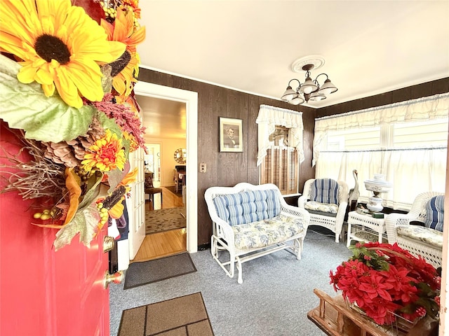 sitting room with an inviting chandelier, carpet, and wood walls