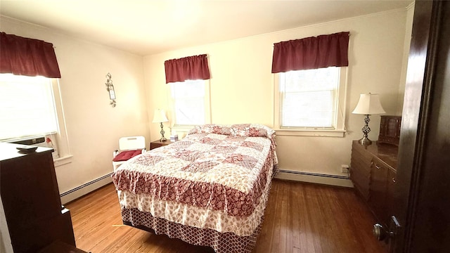 bedroom with wood finished floors and baseboard heating