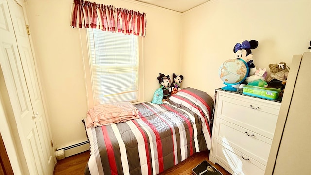 bedroom with dark wood finished floors and a baseboard heating unit