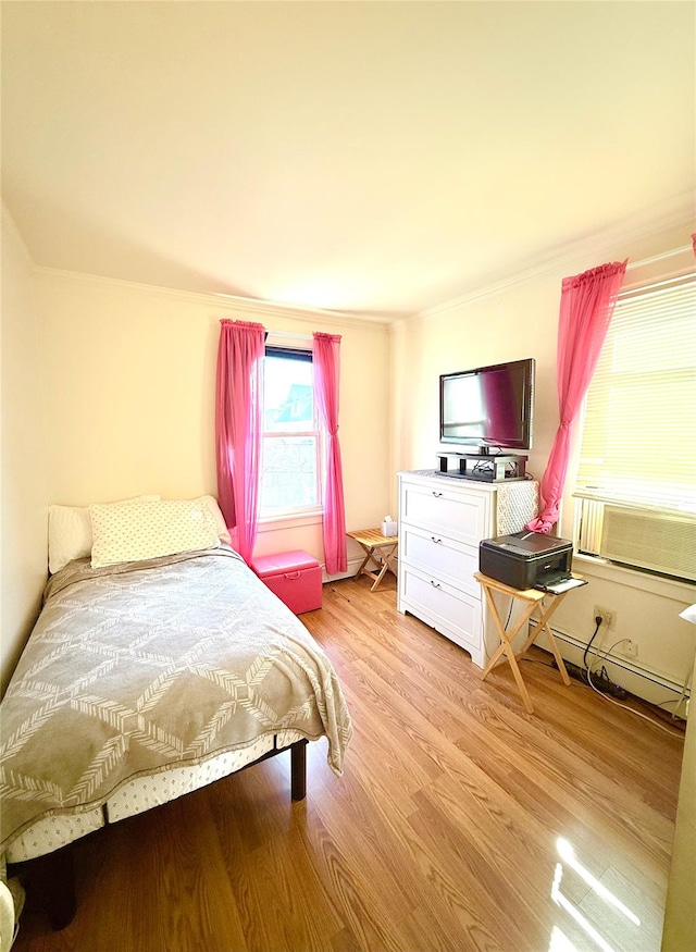 bedroom featuring a baseboard heating unit, light wood-style flooring, and cooling unit